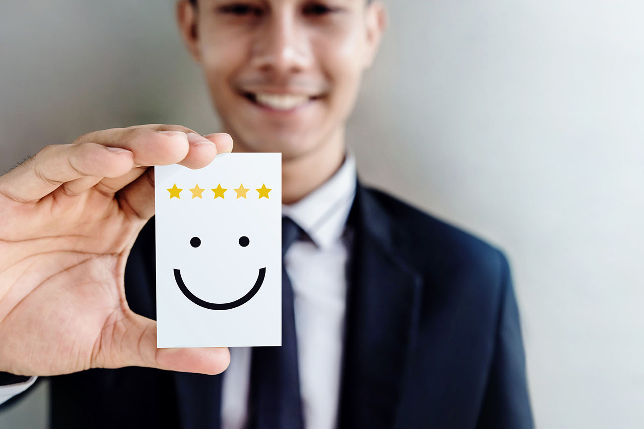 Asian man holding post it note of happy face and 5 stars