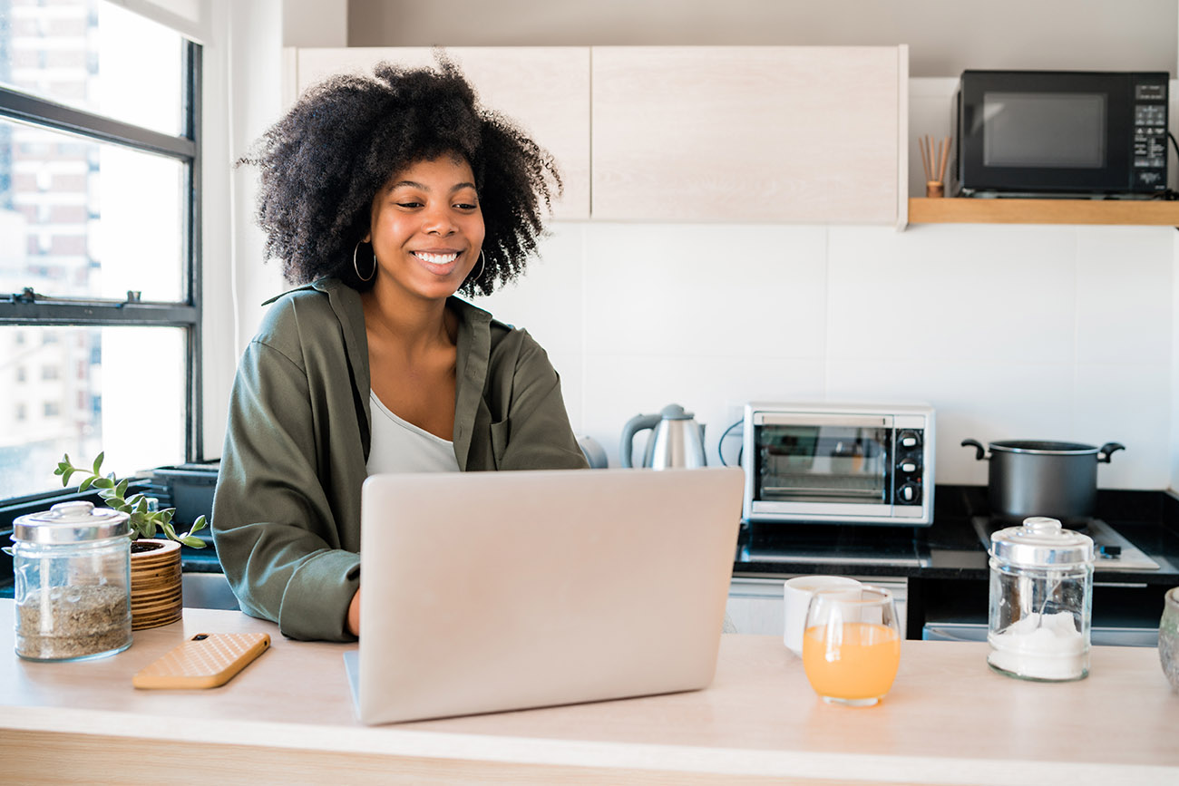 Professional Latina woman working from home kitchen on computer