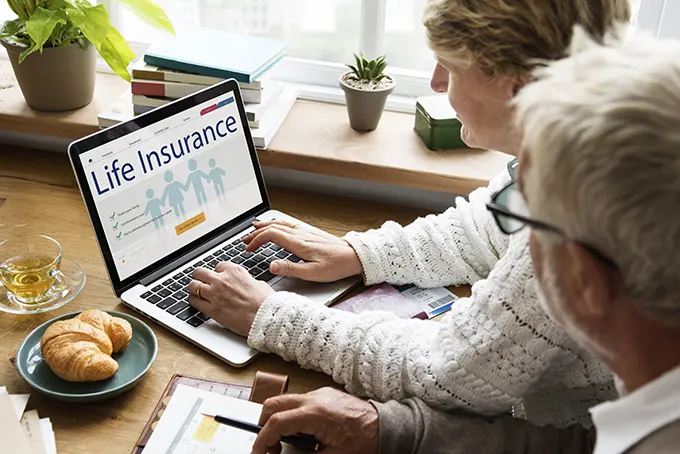 Life insurance couple looking into insurance on laptop