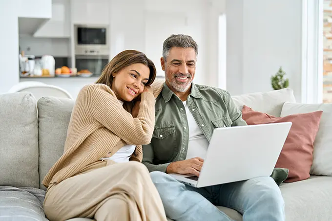 middle-aged-couple-using-computer-on-couch