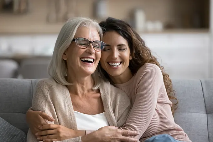 older mom and daughter hugging on couch