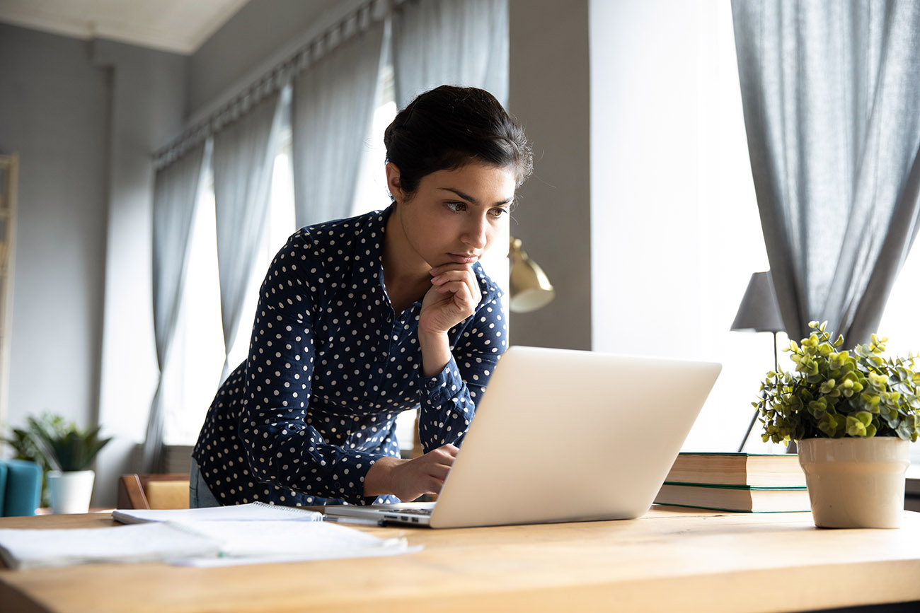 Woman thinking on computer at home