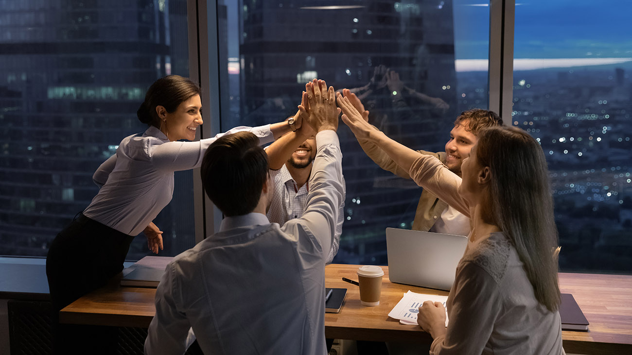 Sales and marketing team celebrating at dusk in office