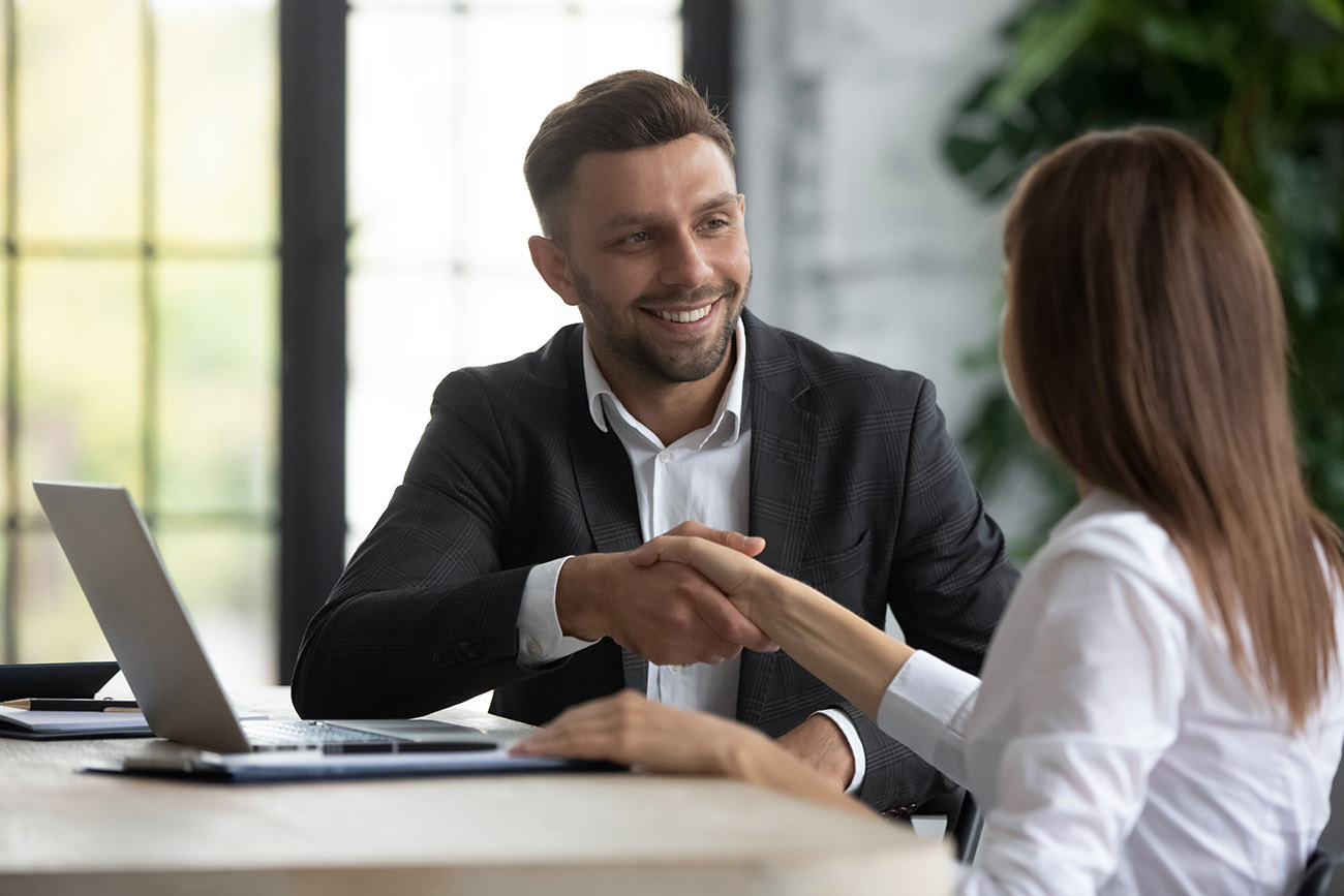 Sales manager shaking hands with client in office