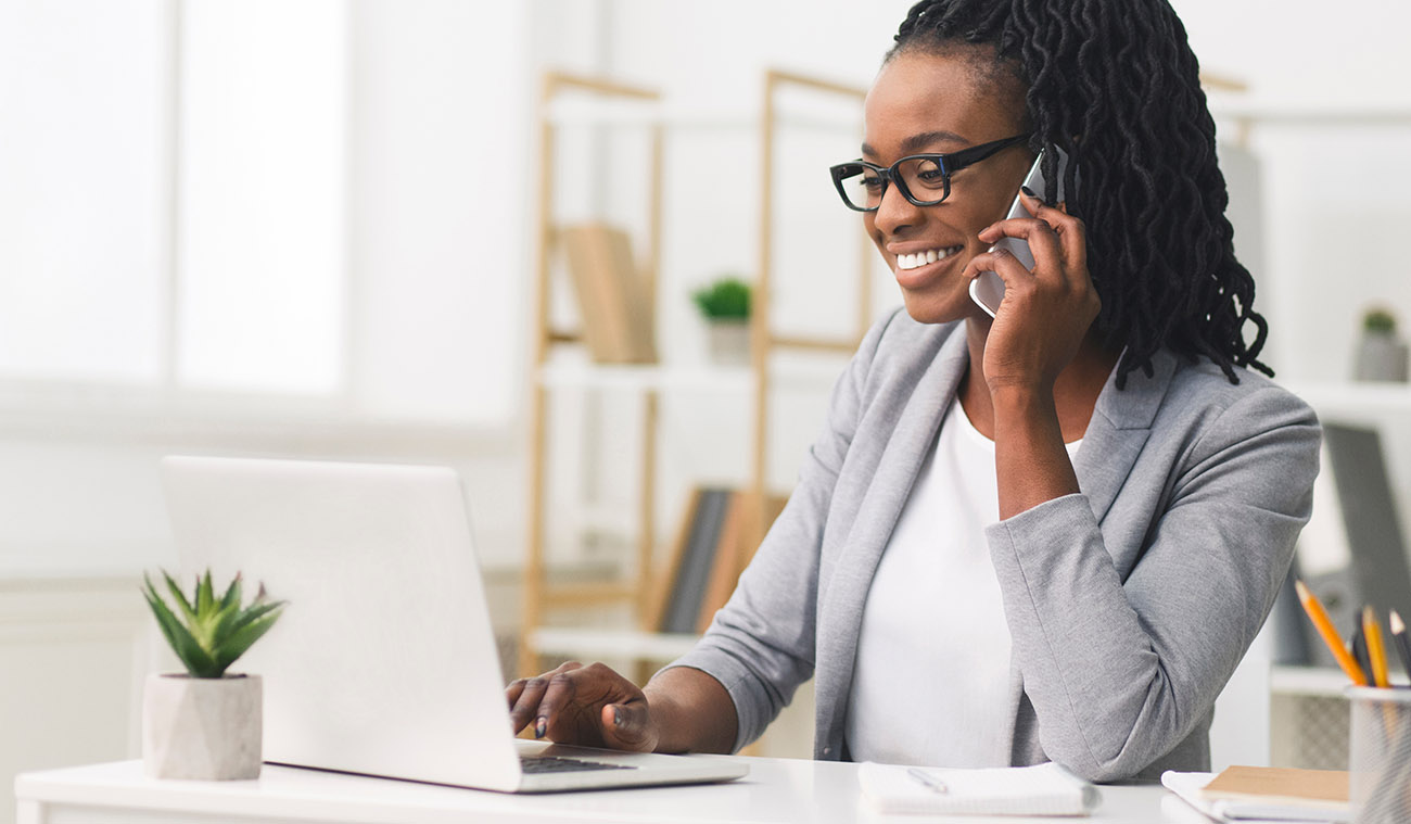 Female business professional speaking with client while using voip services on laptop