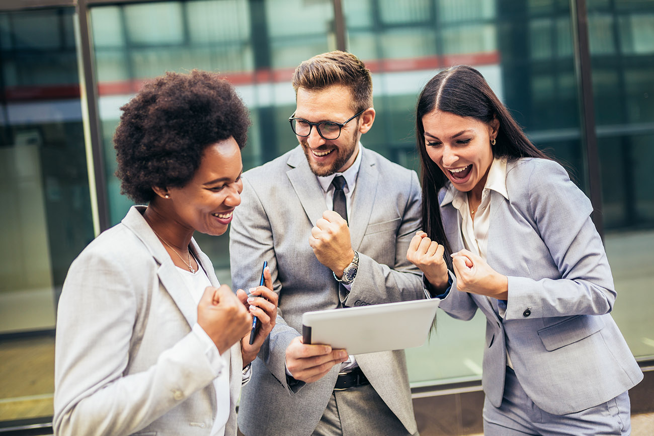 Three professional sales team members celebrating sale close with tablet