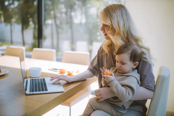 woman carrying baby while working from home