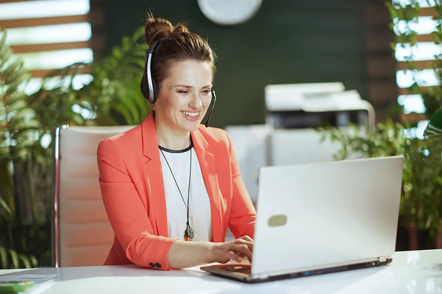 woman using computer and headset in green office