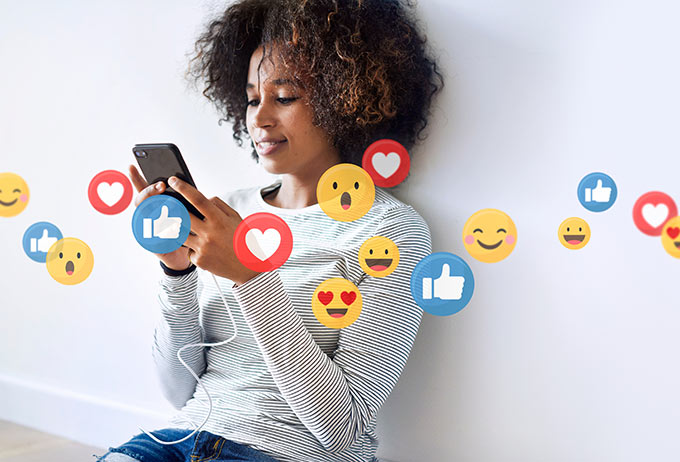 Woman using social media on phone leaning against wall