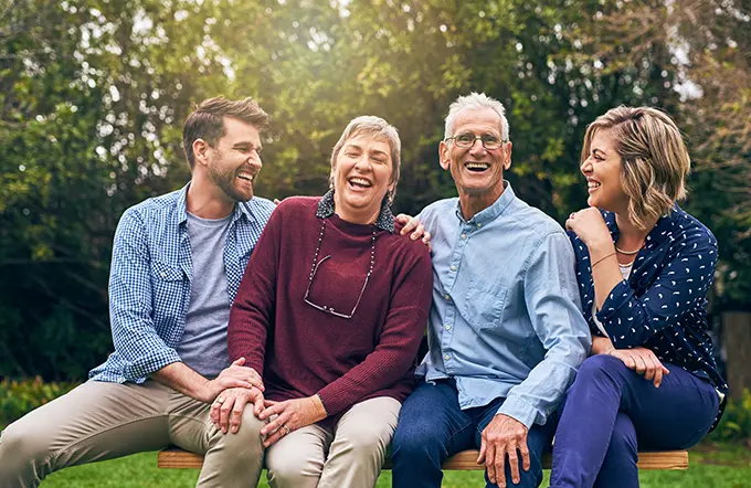 young and old family sitting on park bench