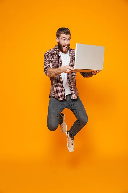 man-jumping-for-joy-holding-computer